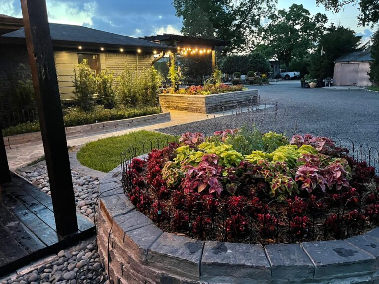 A Houston home lit at dusk with flowering beds along the driveway