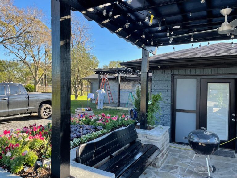 A timber pergola over a paved seating area with planted borders