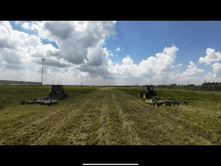 A tractor mowing pasture grass